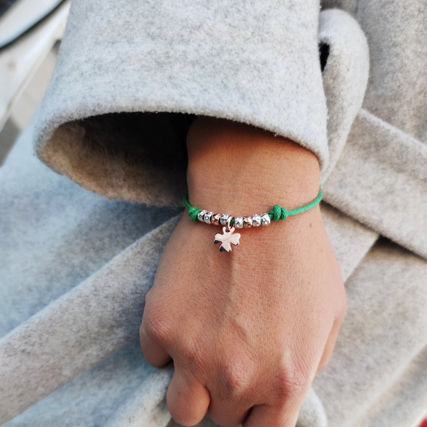 ragazza indossa il bracciale con cordino colorato tipo simil imitazione dodo mariani con granelli e ciondolo charm rosato quadrifoglio porta fortuna idea regalo natale 2020 compleanno battesimo