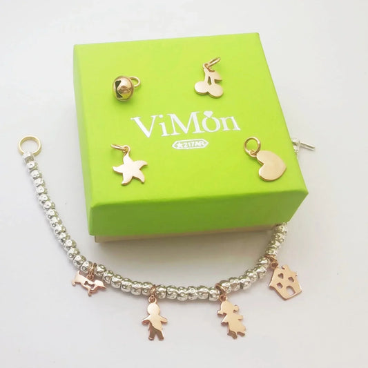 Bracciale con charm in oro rosa giallo e perle argentate ViMon, con ciondoli a forma di stella, bambina, albero e casetta, accanto a scatola verde elegante con logo ViMon
