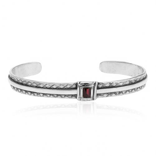 Bracciale rigido da uomo in argento 925 artigianale con lavorazione geometrica e pietra quadrata rossa al centro, fotografato su sfondo bianco professionale.