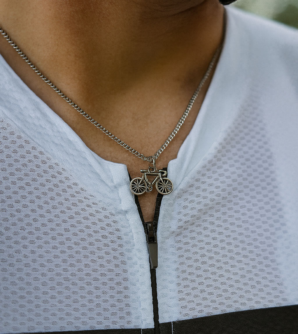 Un ciclista porta una collana d’argento con un ciondolo a forma di bicicletta larga 2 cm e alta 1 cm