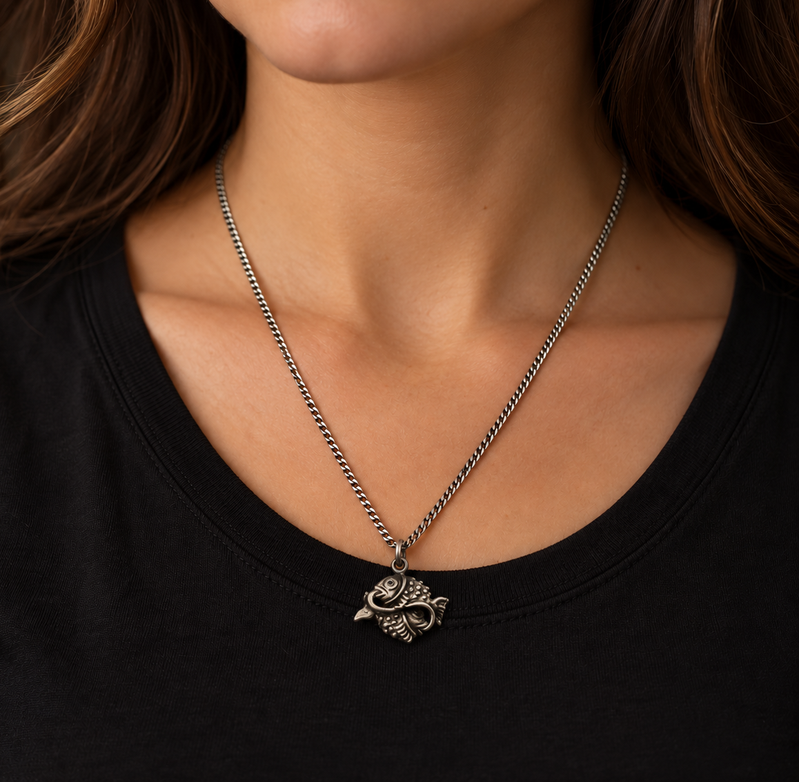 Donna con collana segno zodiacale Pesci in argento 925 brunito, indossata con maglietta nera e catena grumetta.