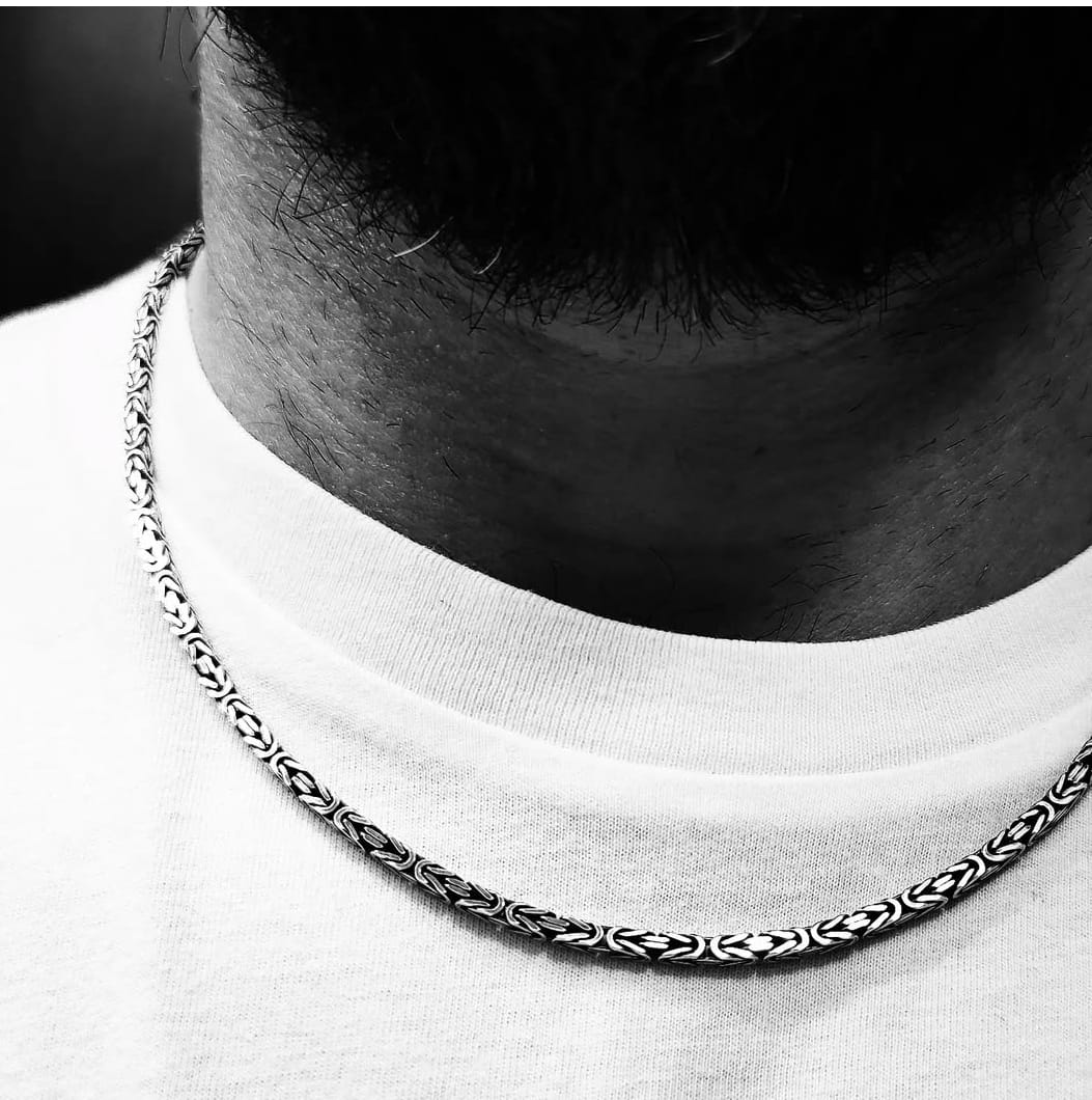 Primo piano di una collana uomo in argento a maglia bizantina indossata, che mette in risalto il design unico