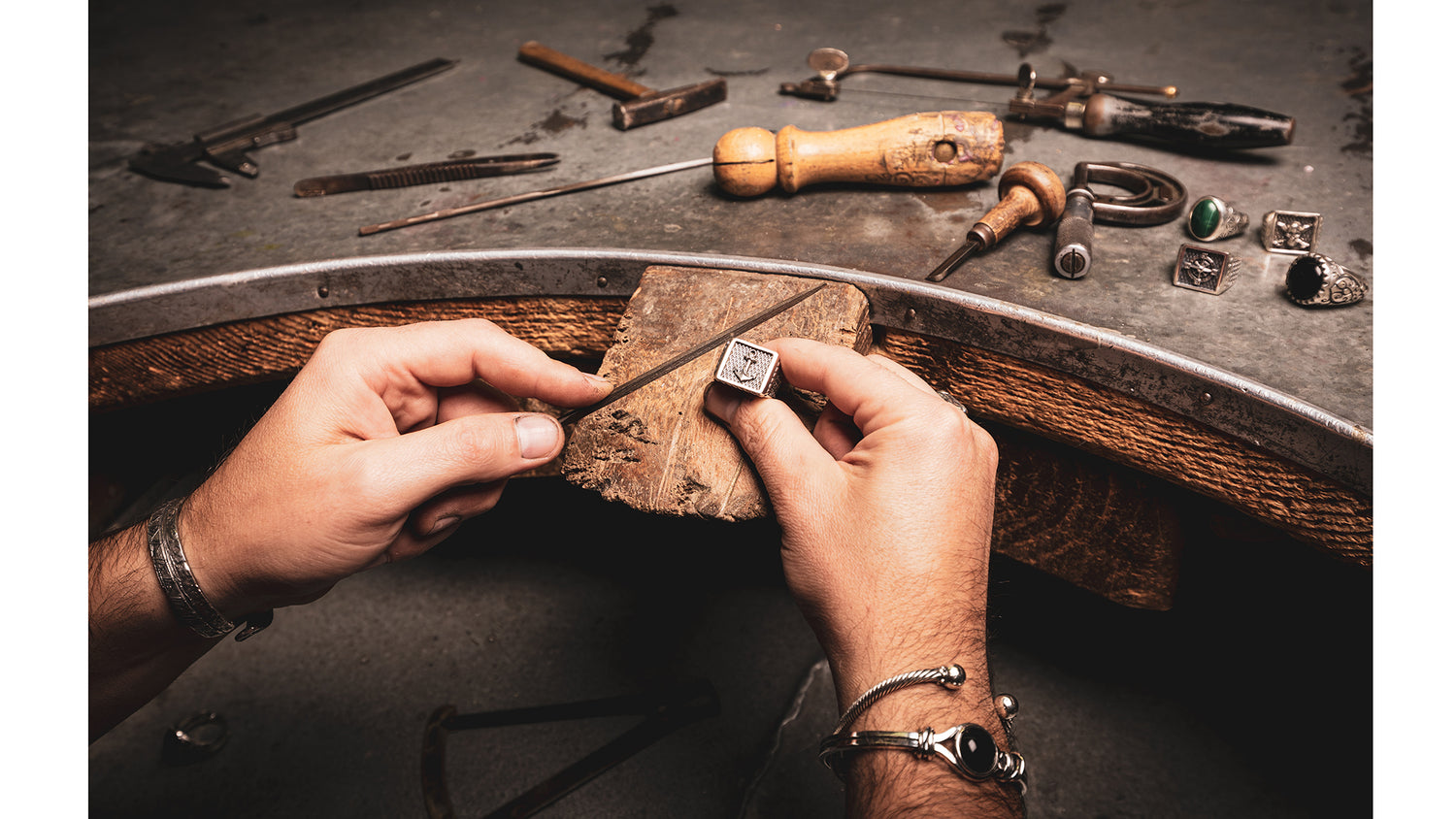 Artigiano orafo che lavora un anello d’argento su banco da lavoro con strumenti di oreficeria tradizionali