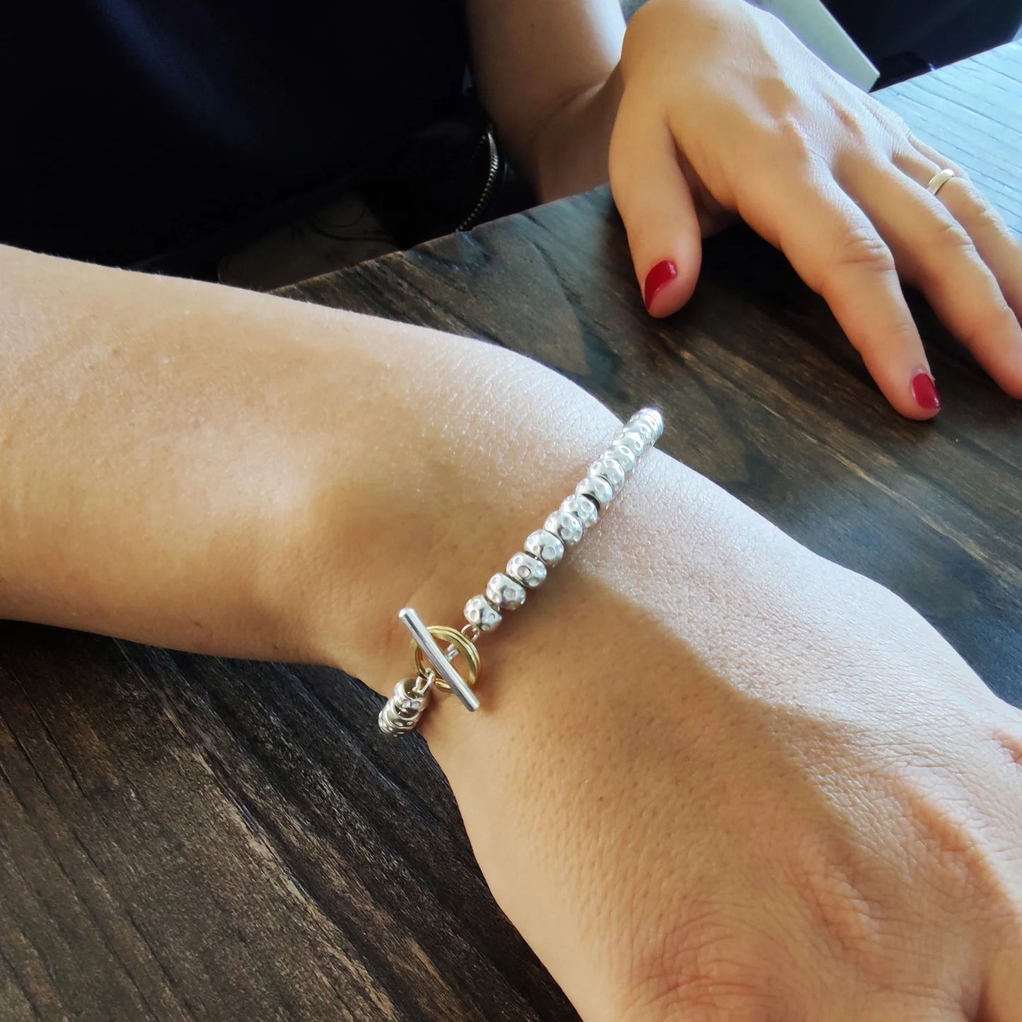 donna indossa al polso il braccialetto tipo dodo con granelli pepite martellate in argento 925