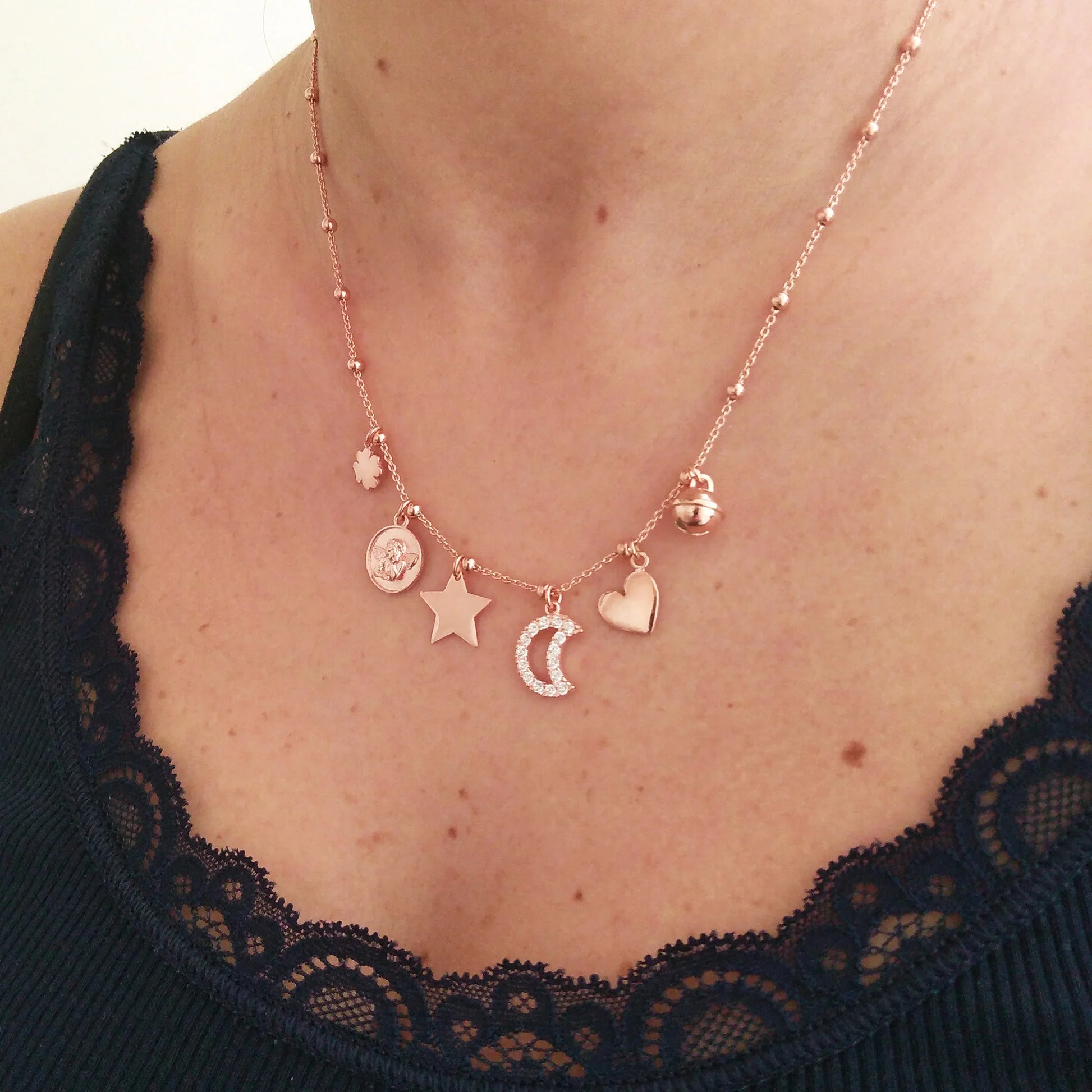 donna ragazza indossa collana in argento 925 placcatura oro rosa con ciondoli rosati  quadrifoglio portafortuna medaglia angelo puttino stella luna cuore campanellino gatto 